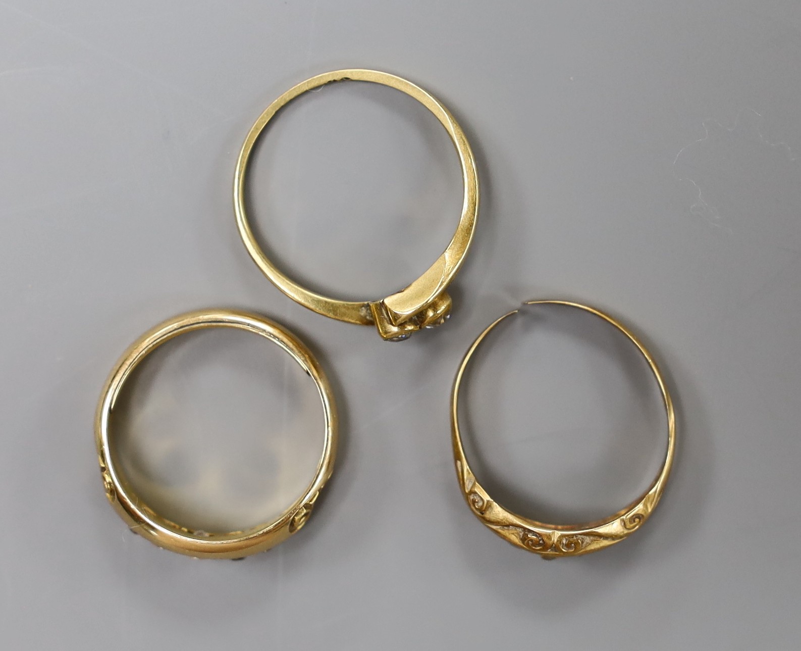 A late Victorian 18ct gold and graduated five stone diamond set half hoop ring, size M/N, a George V 18ct gold and diamond chip set ring (shank cut), gross 6.8 grams and a yellow metal and two stone diamond set crossover